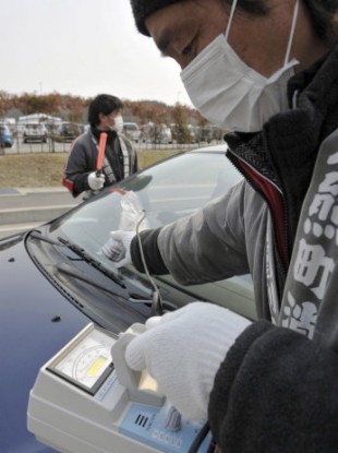 A fireman checks a devise to check the level of radiation on a vehicle before its owner and resident evacuates to other city, in Tamura city, Fukushima prefecture, northeastern Japan, Saturday, April 2, 2011.