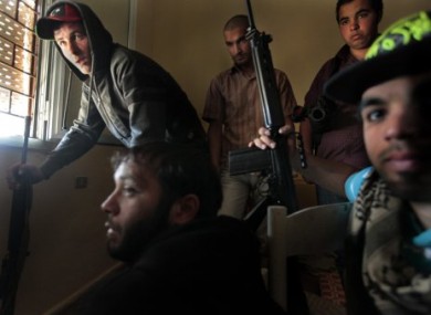 Libyan rebels man a sniper position as they look out through nearly-closed shutters in Misrata.