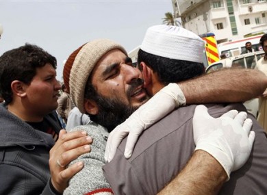 Mourners embrace near the body of a Libyan rebel, whom they say was killed in fighting in Misrata, Libya, Sunday, April 24, 2011.
