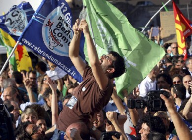 man holds up a bottle of water as campaigners for the 'yes' vote celebrate following results in Italian referendums on water and nuclear power in Rome, Monday, June 13, 2011.