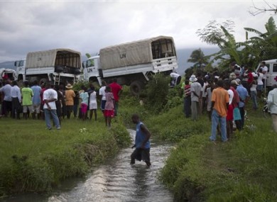 Residents look at UN trucks being used to evacuate people and carry materials from a flooded area after they broke down and blocked the road in Thomazeau, Haiti, Monday June 6, 2011.
