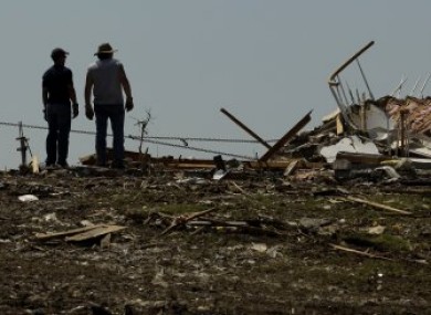 Locals watch as a tractor pulls down what's left of one of their homes in Joplin, Missouri, late last month.
