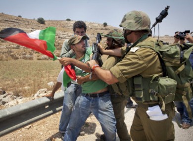 An unidentified protester holding a Palestinian flag scuffles with Israeli security forces during a joint pro-Palestinian demonstration held by foreign, Israeli and Palestinian demonstrators in the West Bank village of Nabi Saleh, Saturday, July 9, 2011.