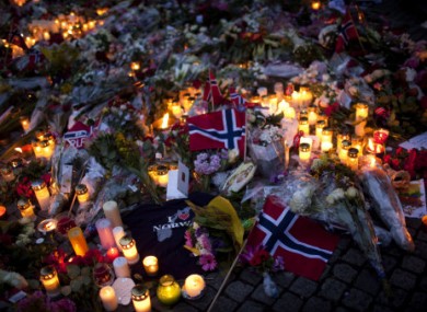 Norwegian flags, flowers and candles are seen at the ground as people gather to pay tribute to victims of the twin attacks near the Domkirke church on Friday, in central Oslo, Norway, Saturday, July 23, 2011.