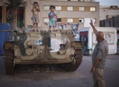 A man asks two kids, over an armored car, to make the victory sign at the rebel-held town of Benghazi, Libya, Tuesday, Aug. 10, 2011.