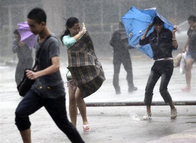 People brave strong winds and rain on a street as a typhoon hit Haikou in south China's Hainan province, Thursday, Sept. 29, 2011.