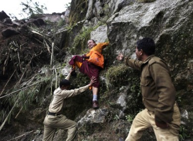 Members of Indian Army help a Buddhist monk to descend a huge landslide following Sunday's 6.9 magnitude earthquake in Sikkim, India.