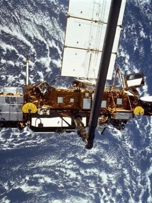 This is the STS-48 onboard photo of the Upper Atmosphere Research Satellite (UARS) in the grasp of the RMS (Remote Manipulator System) during deployment, from the shuttle in September 1991.
