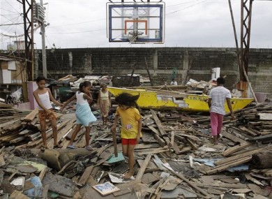 Residents walk on debris from damaged houses and a boat along a coastal village in Navotas, north of Manila, Philippines on Sunday Oct. 2, 2011.