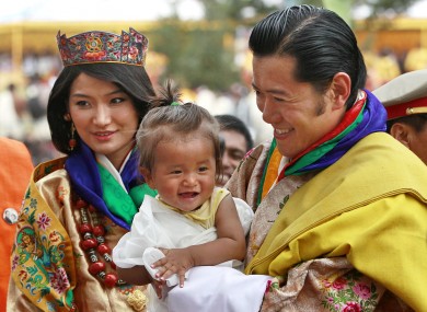 King Jigme Khesar Namgyal Wangchuck, right, holds a young child as he greets locals with Queen Jetsun Pema