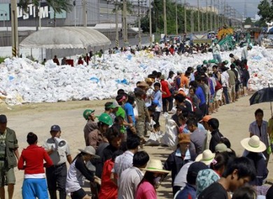 Factory workers join hands in stacking sandbags to make flood barriers at Nawa Nakorn industrial district on the outskirts of Bangkok, Thailand Sunday, Oct. 16, 2011.
