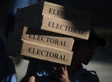 A police officer carries boxes filled with ballots