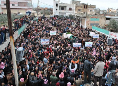 Mourners at a funeral in February in the Rastan neighbourhood of Homs carry signs telling the people in Baba Amr to