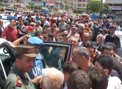 A UN observer and Syrian army officer, left, listen to Syrian citizens during their visit to the pro-Syrian regime neighborhoods, in Homs province yesterday.