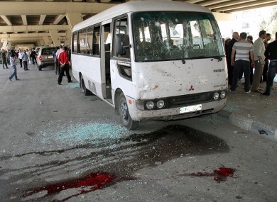Syrian investigators, right, gather next to a damaged police bus that was attacked by an explosion in the Midan neighborhood of Damascus, Syria, on Friday April 27, 2012