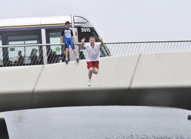 Lee Byrne with local children from Dublin as they jump off Mayor Street Bridge in the Royal Canal in Dublin earlier today.