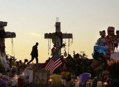 A man walks on a hill near crosses set up at the memorial to victims of the Aurora, Colo., movie theater shooting, early Friday, July 27, 2012
