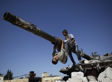 Two boys play on a Syrian military tank which was destroyed during fighting in Azaz on the outskirts of Aleppo.