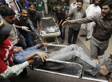 People rush an injured man to an emergency ward of a local hospital in Karachi, Pakistan after the attacks
