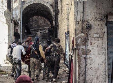 Free Syrian Army fighters carry a wounded colleague through the town of Harem in Syria