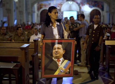 A woman carries an image of Hugo Chavez before a mass in support of him in Cuba yesterday