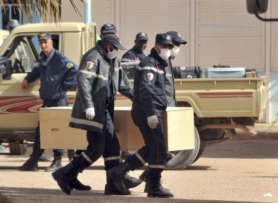 Algerian firemen carry a coffin containing a person killed during the hostage situation earlier today