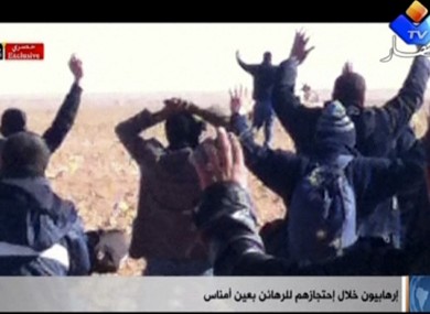 In this image made from video, a group of people believed to be hostages kneel in the sand with their hands in the air at an unknown location in Algeria.
