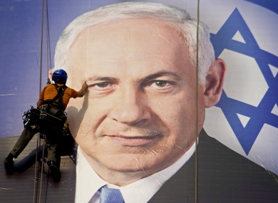 A worker hangs a huge poster with an image of Israel's Prime Minister Benjamin Netanyahu overlooking the Ayalon freeway in Tel Aviv