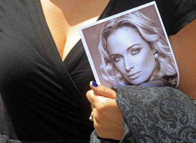 A woman holds a photo of Reeva Steenkamp, as she leaves her funeral, in Port Elizabeth earlier.