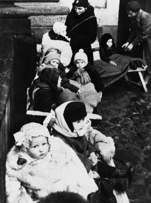 Heavily clothed for protection against the bitter weather, Russian children take cover in an air raid shelter in a public park in Leningrad, Russia, during a raid by Nazi planes: 18/04/1942.