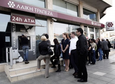 People queue at an ATM outside a closed Laiki Bank branch in Nicosia on Thursday