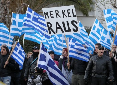 Supporters of the far-right party Golden Dawn with Greek flags hold signs reading 'Merkel out' in German, during a protest outside the Germany embassy in Athens on Friday.