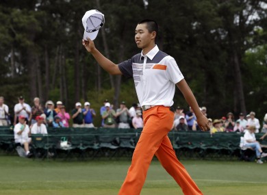 Amateur Guan Tianlang, of China, waves his cap after putting out on the 18th hole during the fourth round of the Masters golf tournament.
