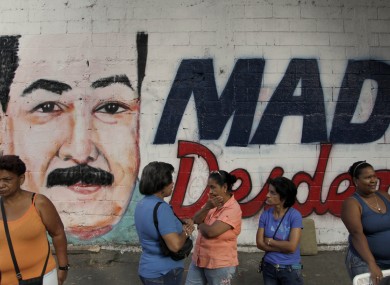 Residents wait to enter a polling station where a nearby wall is covered with a mural of interim President Nicolas Maduro during the presidential election in Caracas, Venezuela, today.