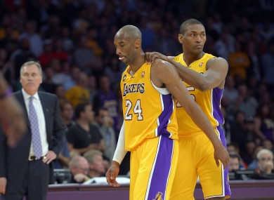 Los Angeles Lakers guard Kobe Bryant, center, is consoled by forward Metta World Peace, right, as head coach Mike D'Antoni looks on after being injured during the second half of their NBA basketball game against the Golden State Warriors.