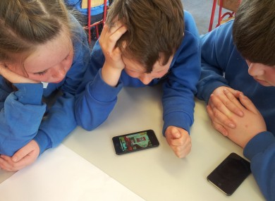 Sixth class children helping junior infants develop early reading skills on iPods.