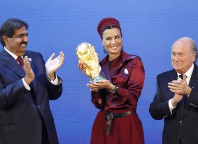 Sheikh Hamad bin Khalifa Al-Thani, Emir of Qatar, left, and Sheika Mozah bint Nasser al-Misned hold the World Cup trophy as FIFA President Joseph Blatter, right, applauds after the announcement of Qatar hosting the Finals.