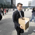A worker holding a box, leaves the Lehman Brothers headquarters at Canary Wharf in London.<span class=