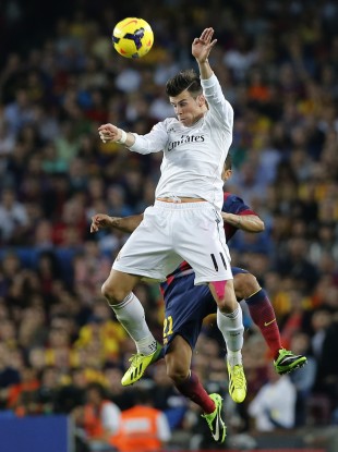 Real Madrid's Gareth Bale jumps for the ball with Barcelona's Adriano Correia.