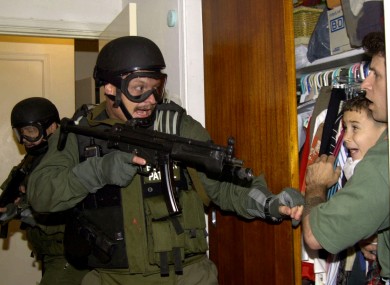 Elian Gonzalez is held by one of the two men who rescued him from the ocean as US government officials search the home in April 2000.