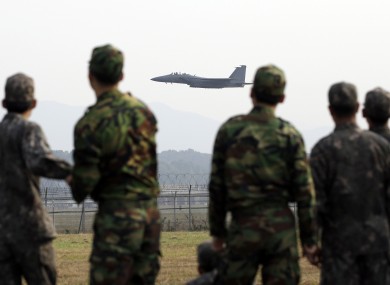 A South Korean Air Force F-15K fighter flies as soldiers watch.