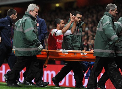 Walcott gestures to Spurs fans while being stretchered off.