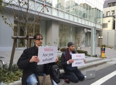Two bitcoin traders hold protest signs as they conduct a sit-in in front of the office tower housing MtGox in Tokyo.