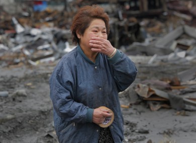 Reiko Miura, 68, cries as she looks for her sister's son at a tsunami-hit area in Otsuchi, Iwate Prefecture.