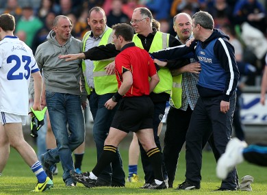 Referee Derek O'Mahoney leaves the field under escort.
