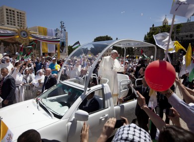 Pope Francis waves on his way to a mass in Manger Square next to the Church of the Nativity, traditionally believed to be the birthplace of Jesus Christ in the Palestinian West Bank town of Bethlehem.