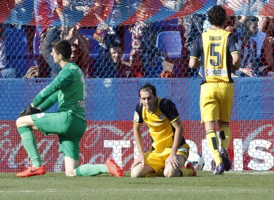 Atletico de Madrid's goalkeeper Thibaut Courtois from Belgium, left, and Diego Godin from Uruguay, center, stay on the ground after Levante scored their second goal.