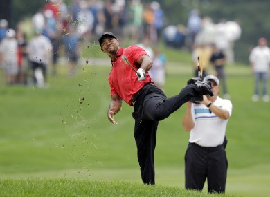 Woods has an awkward follow through after hitting from the lip of a fairway bunker on the second hole.