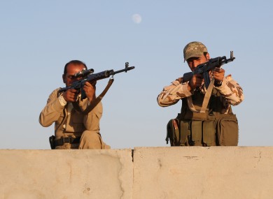 Kurdish Peshmerga fighters stand guard during airstrikes targeting Islamic State militants.
