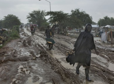 Photo dated July 24, 2014: People trudge along the main passageway through the UN's Malakal Camp for Internally Displaced People during the wet season.